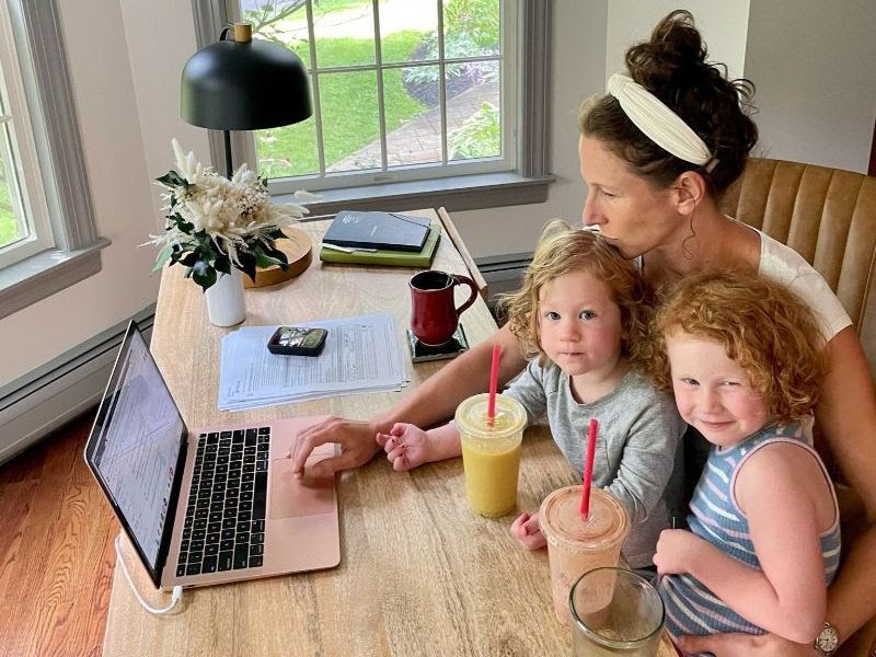 Move This World Founder and CEO Sara Potler LaHayne sitting at her desk with her daughters